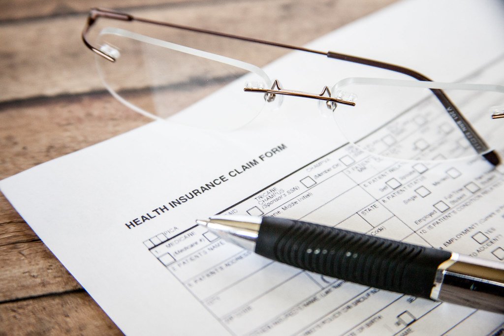 questionnaire-sante-assurance-emprunteur-loi-lemoine Formulaire de déclaration de santé, stylo et lunettes posés sur une table, illustrant le questionnaire de santé demandé pour une assurance emprunteur.