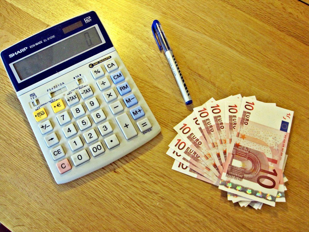 taea-taux-annuel-effectif-assurance-emprunteur Calculatrice avec touche pourcentage, stylo et billets de 10 euros posés sur une table, illustrant le calcul du TAEA en assurance emprunteur.