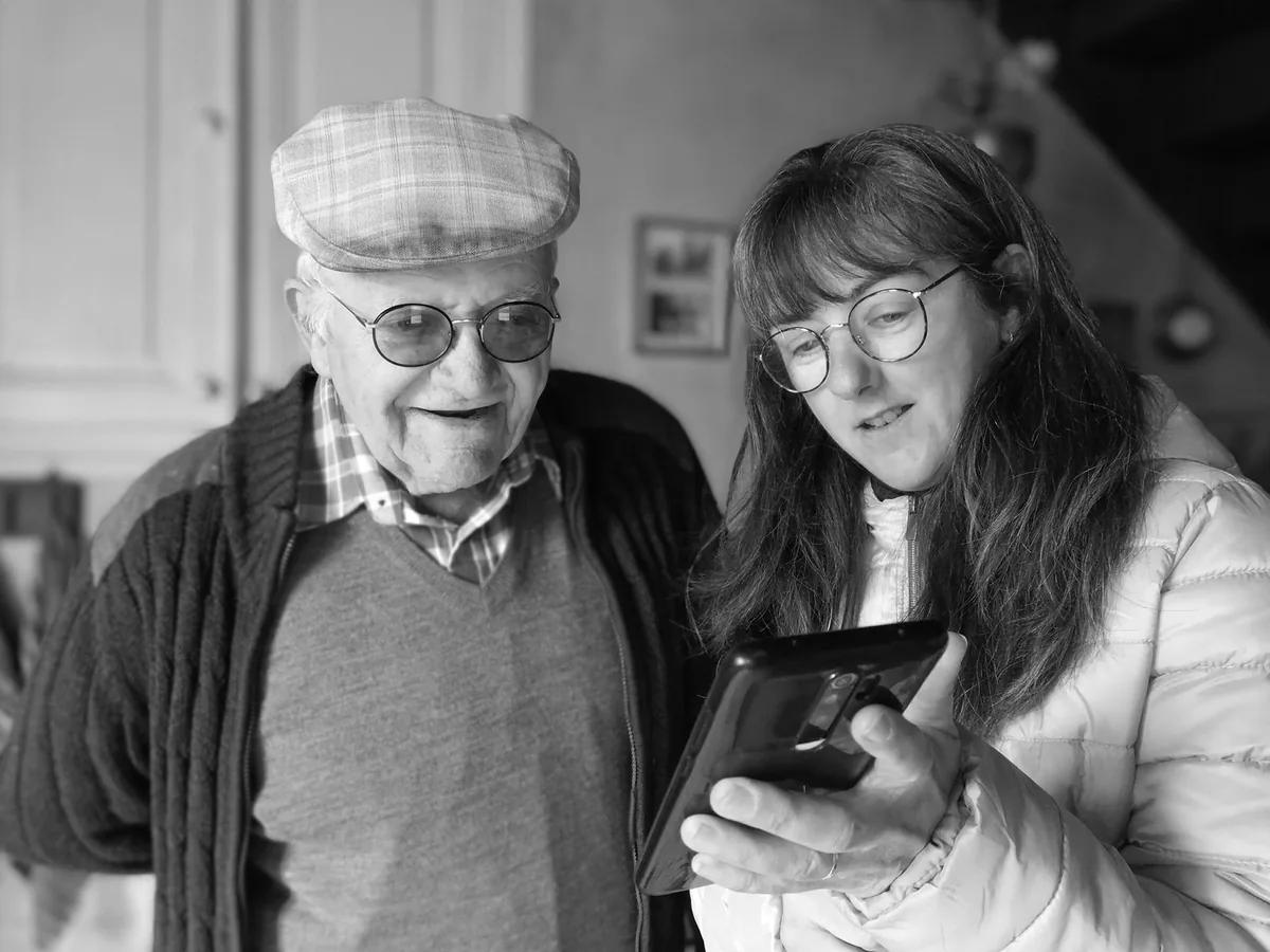 Un opticien présente des montures de lunettes à une cliente devant un présentoir de magasin