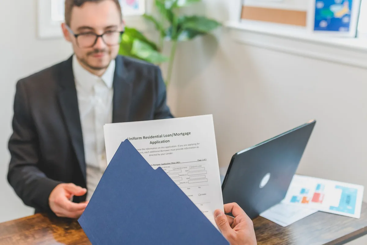 Une personne relit un dossier de prêt et des courriers posés sur une table de travail