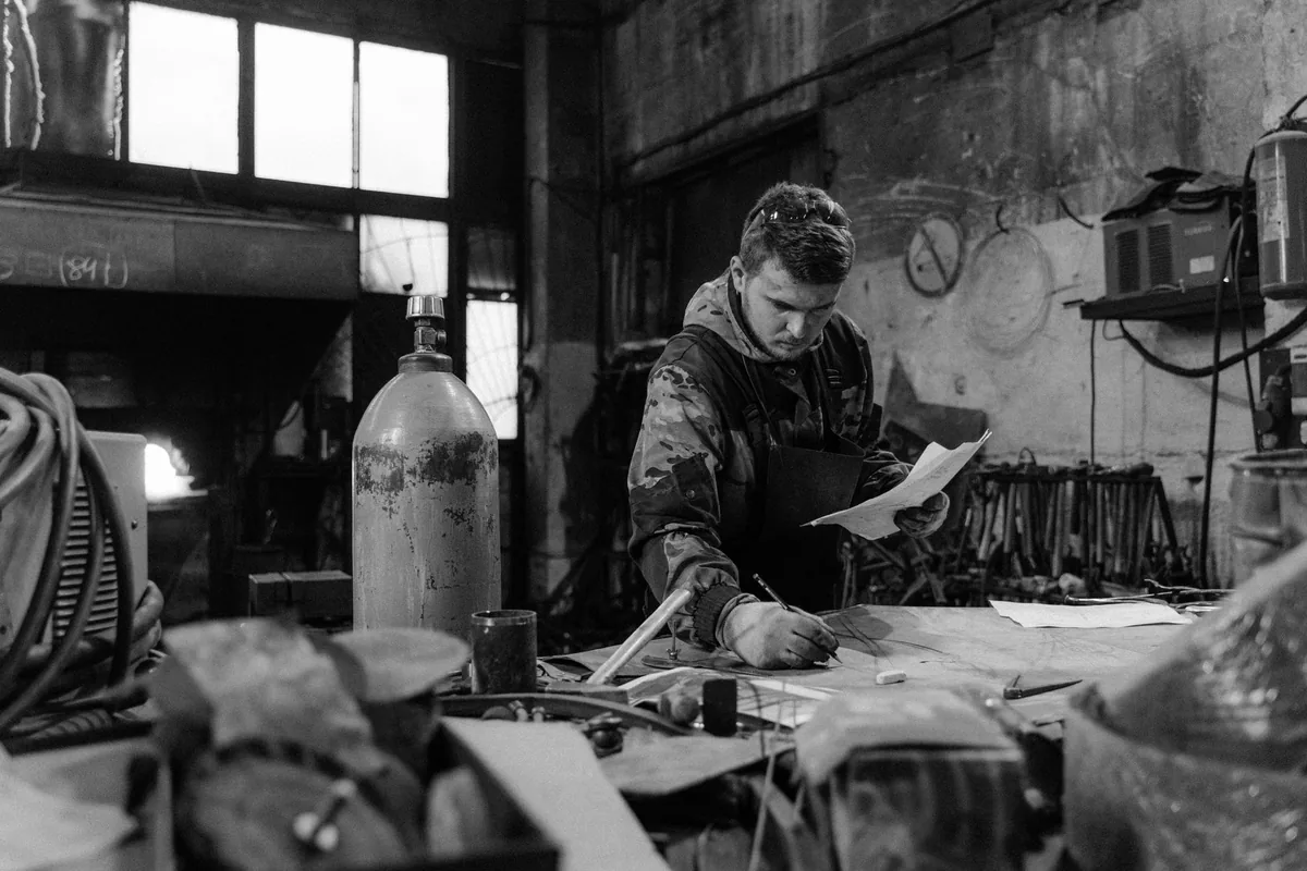 Un artisan indépendant consulte des documents d'assurance et une facture à son bureau d'atelier