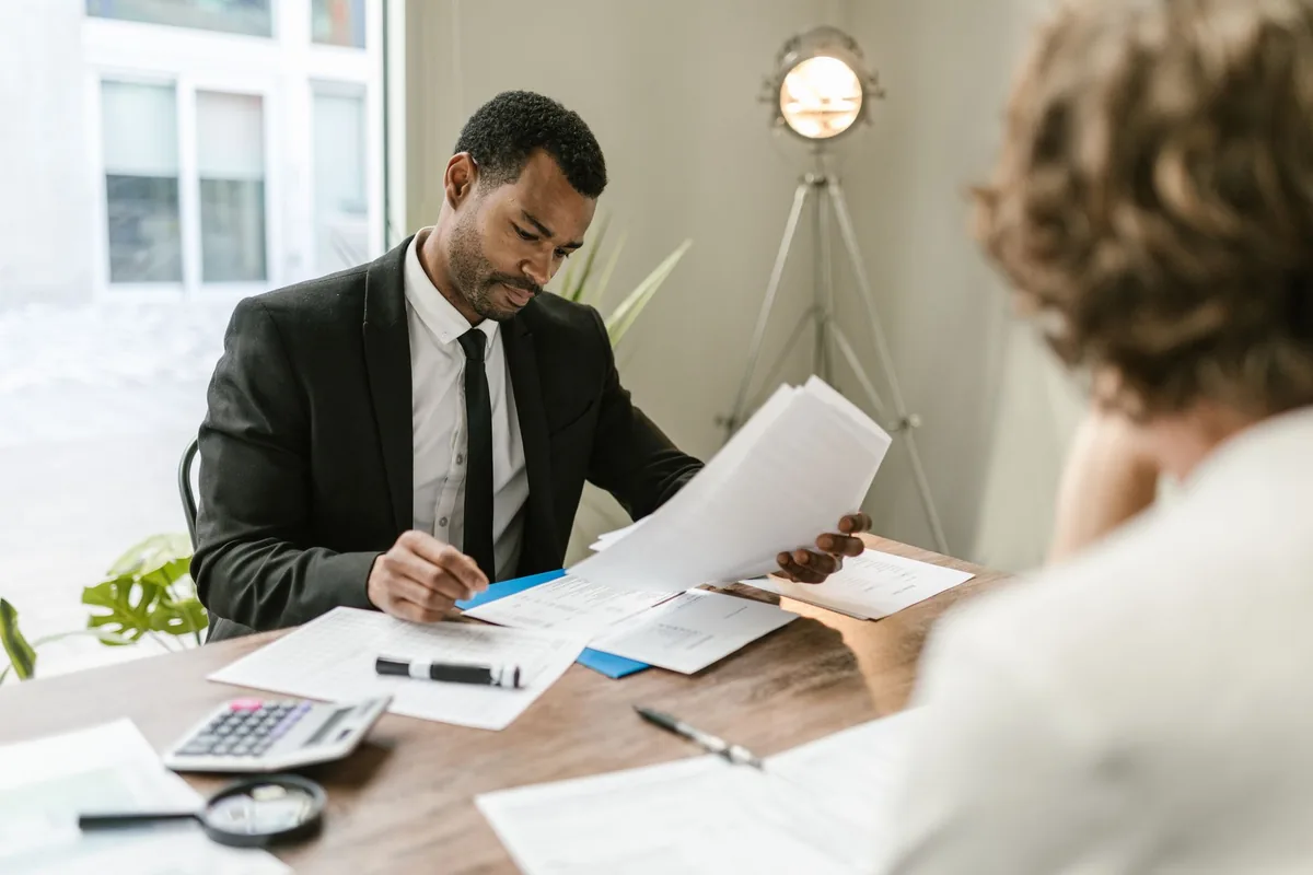 Un homme d'une cinquantaine d'années examine des documents de prêt immobilier avec un conseiller bancaire