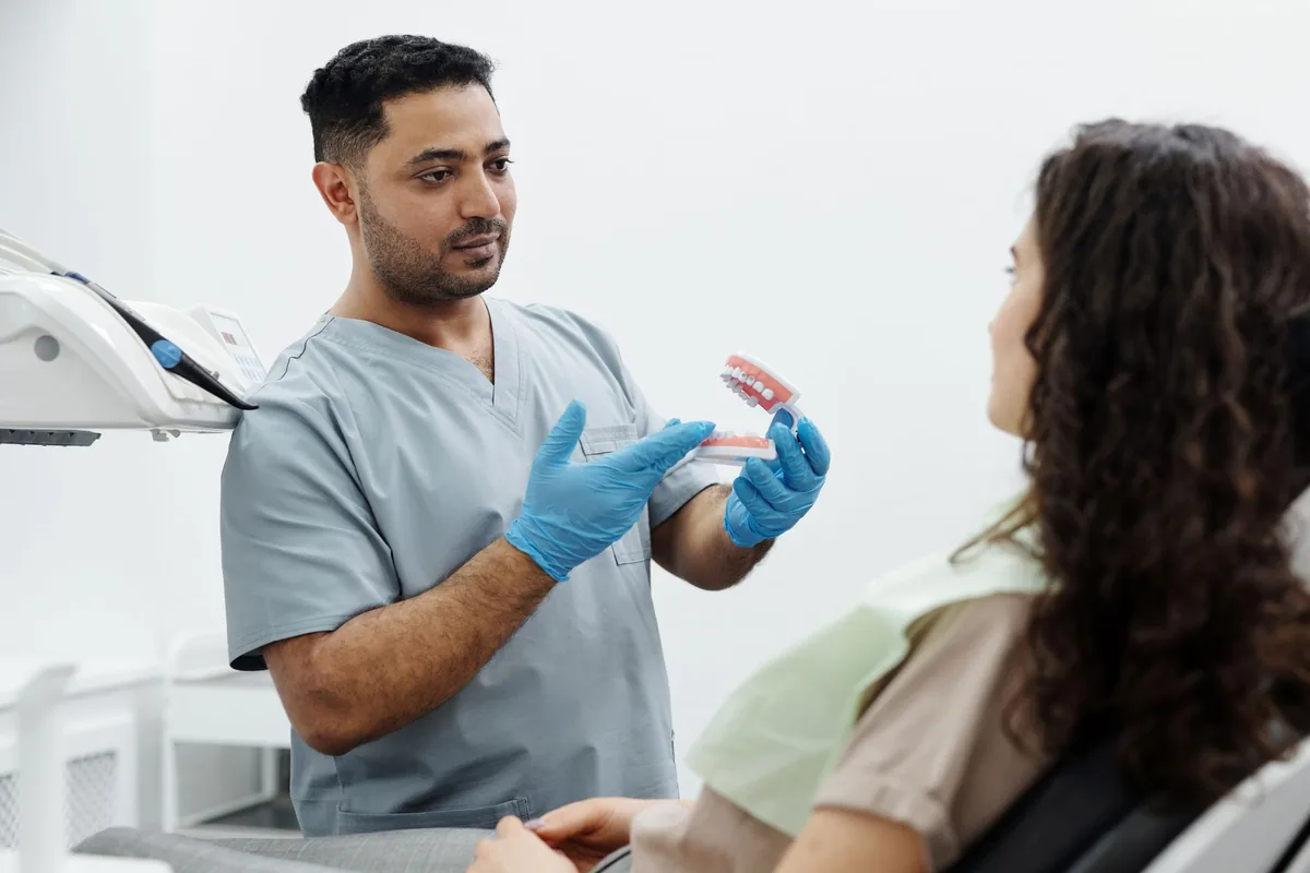 Un chirurgien-dentiste présente un modèle de bridge de trois éléments à un patient assis dans son cabinet