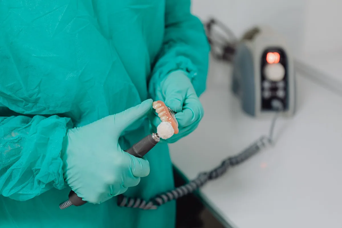 Un prothésiste dentaire tient une prothèse amovible complète en résine dans son laboratoire