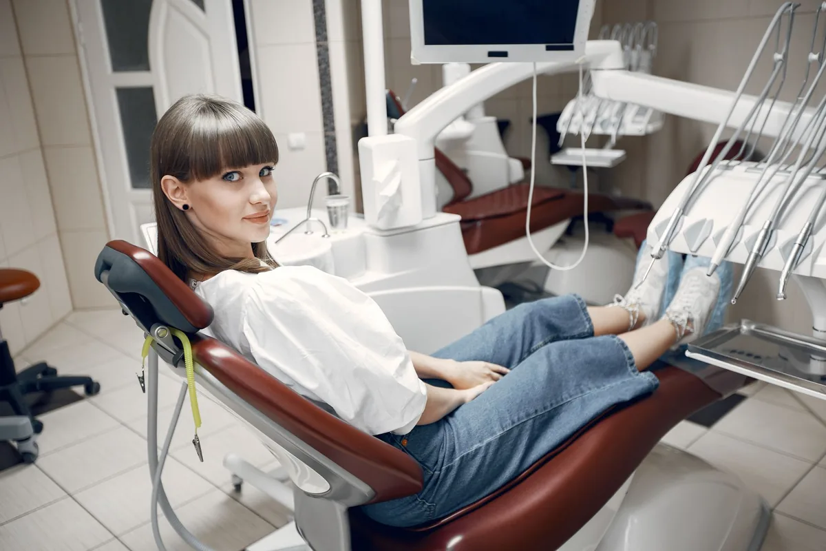 Une patiente adulte portant un appareil dentaire fixe assise dans le fauteuil d'un cabinet d'orthodontie