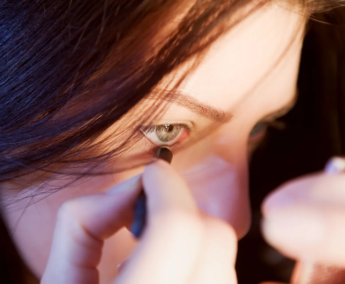 Un optométriste ajuste une lentille de contact sur l'oeil d'un patient lors d'un examen visuel